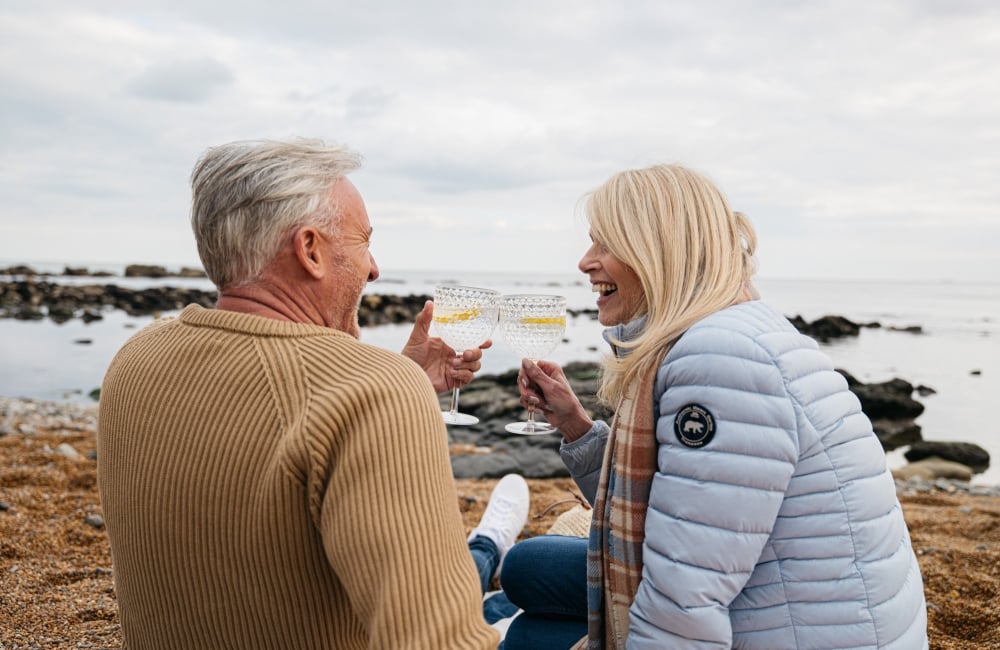 a smiling couple clink glasses of gin