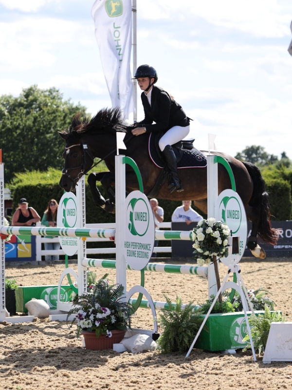 wide shot of Rubi on her pony, jumping