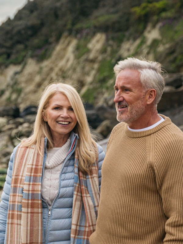 couple in winter clothes walking near beach