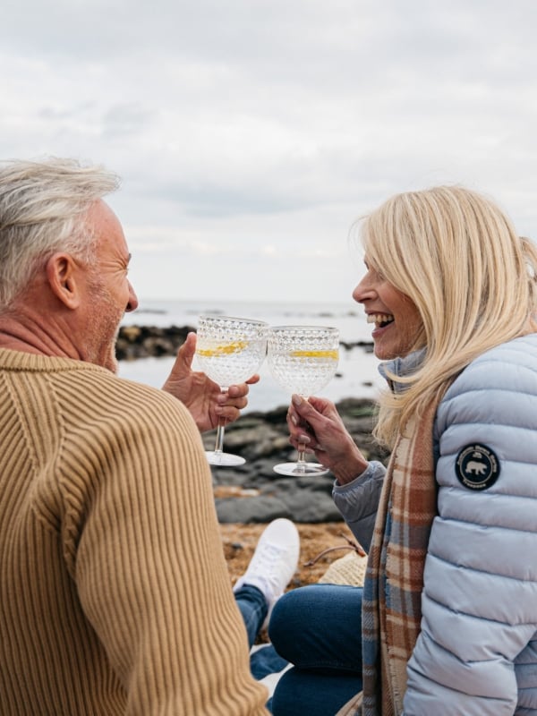 a smiling couple clink glasses of gin