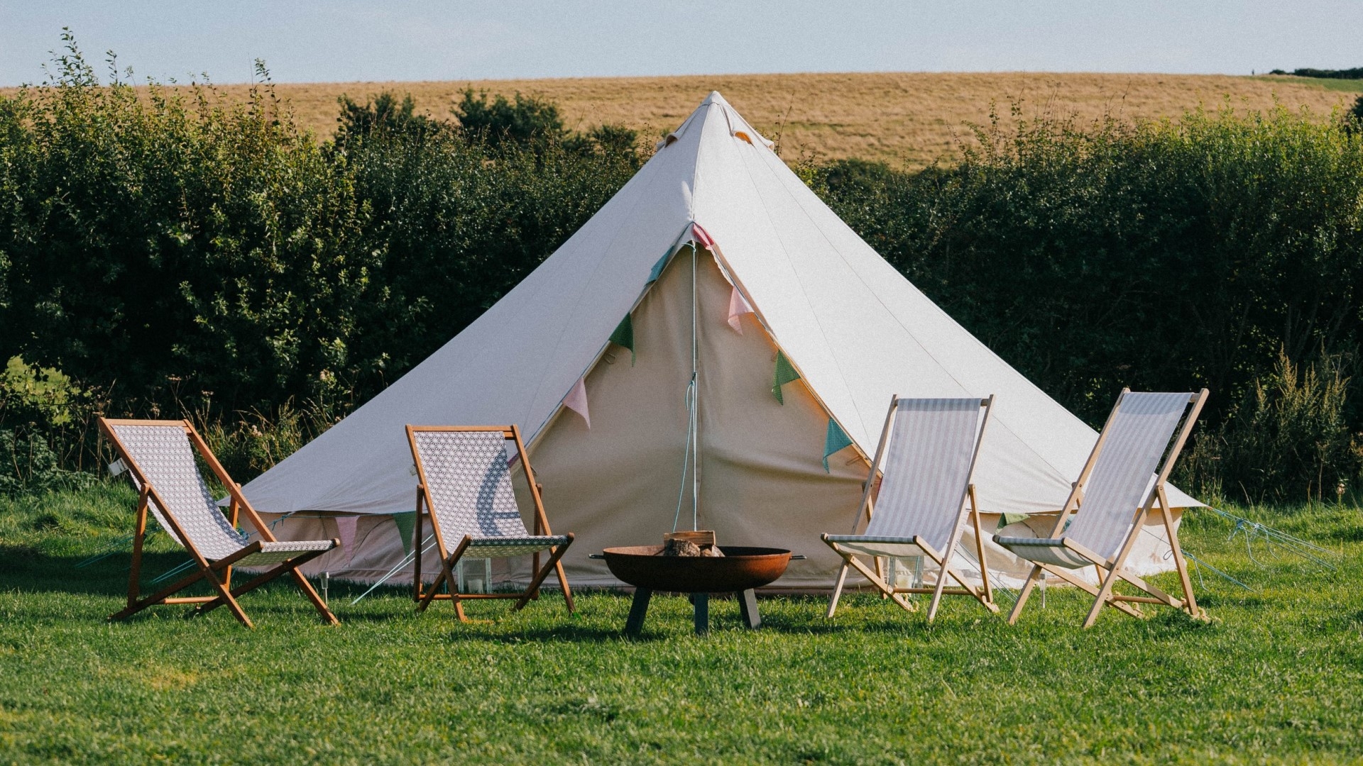 large white bell tent with deckchairs out front