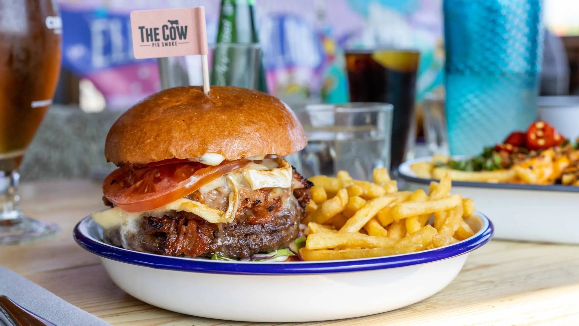 a toasted brioche bun with beef burger and melted cheese with a side of fries