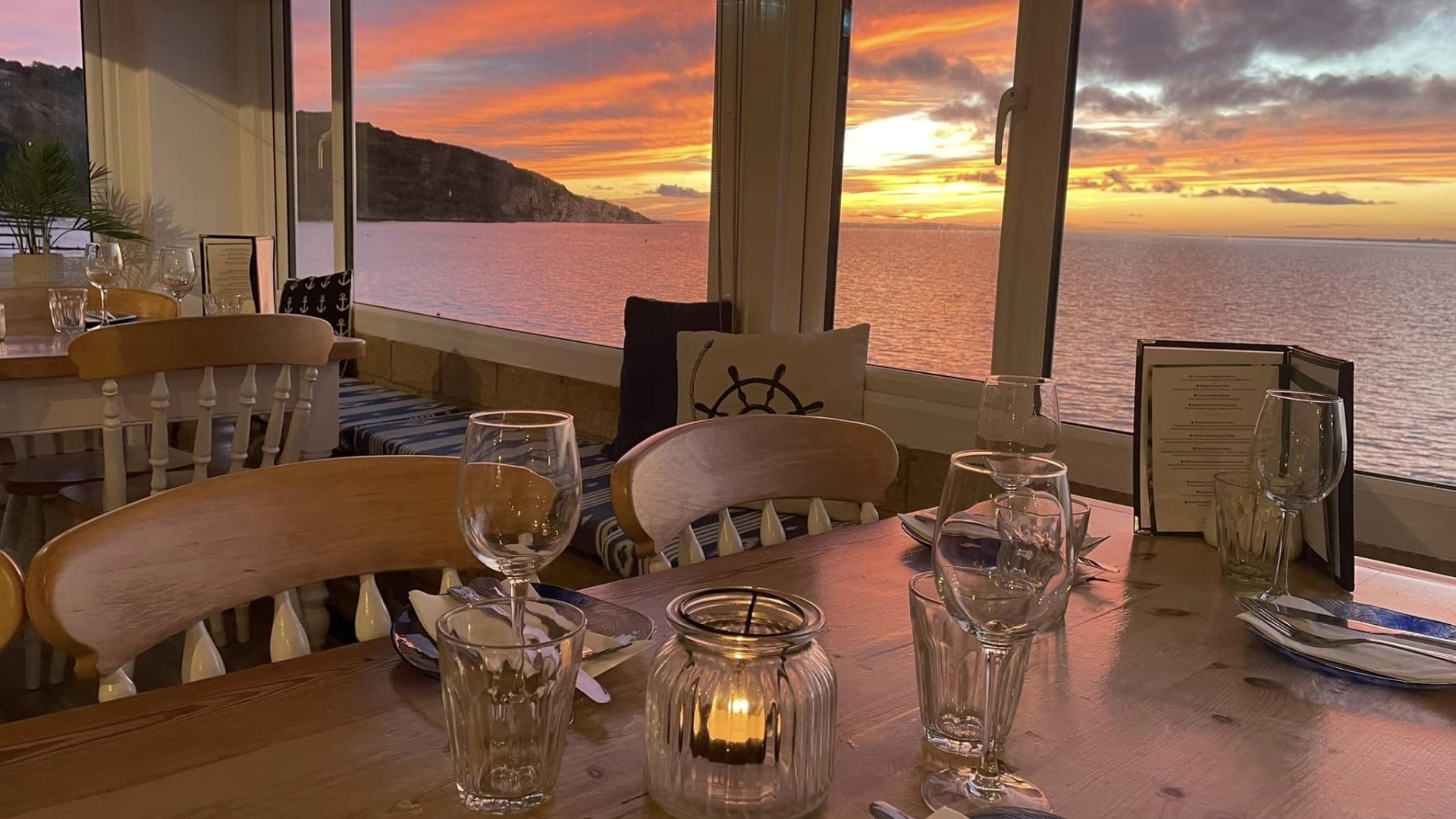 a dining table with sunset visible through the window