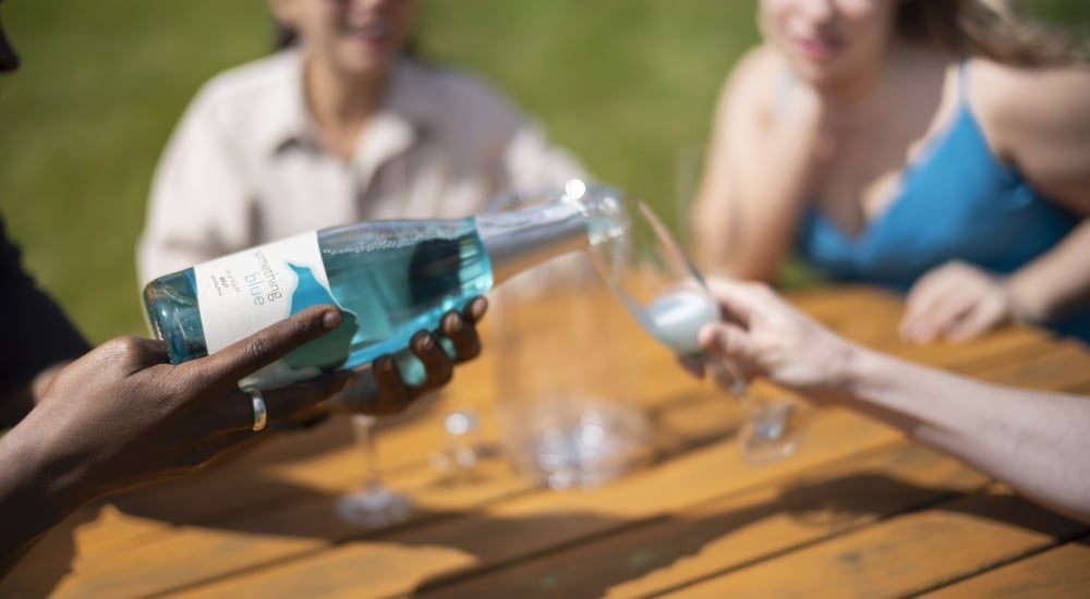 a bottle of 'something blue' sparkling wine being poured into a flute glass