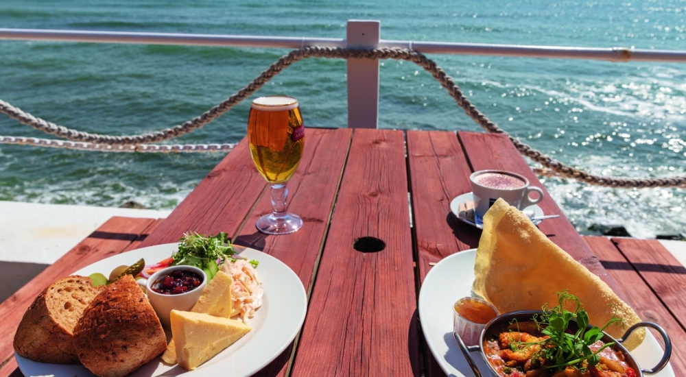 meals on a picnic bench with the sea in the background